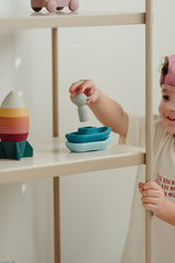 Little boy playing with boatman toy on shelves
