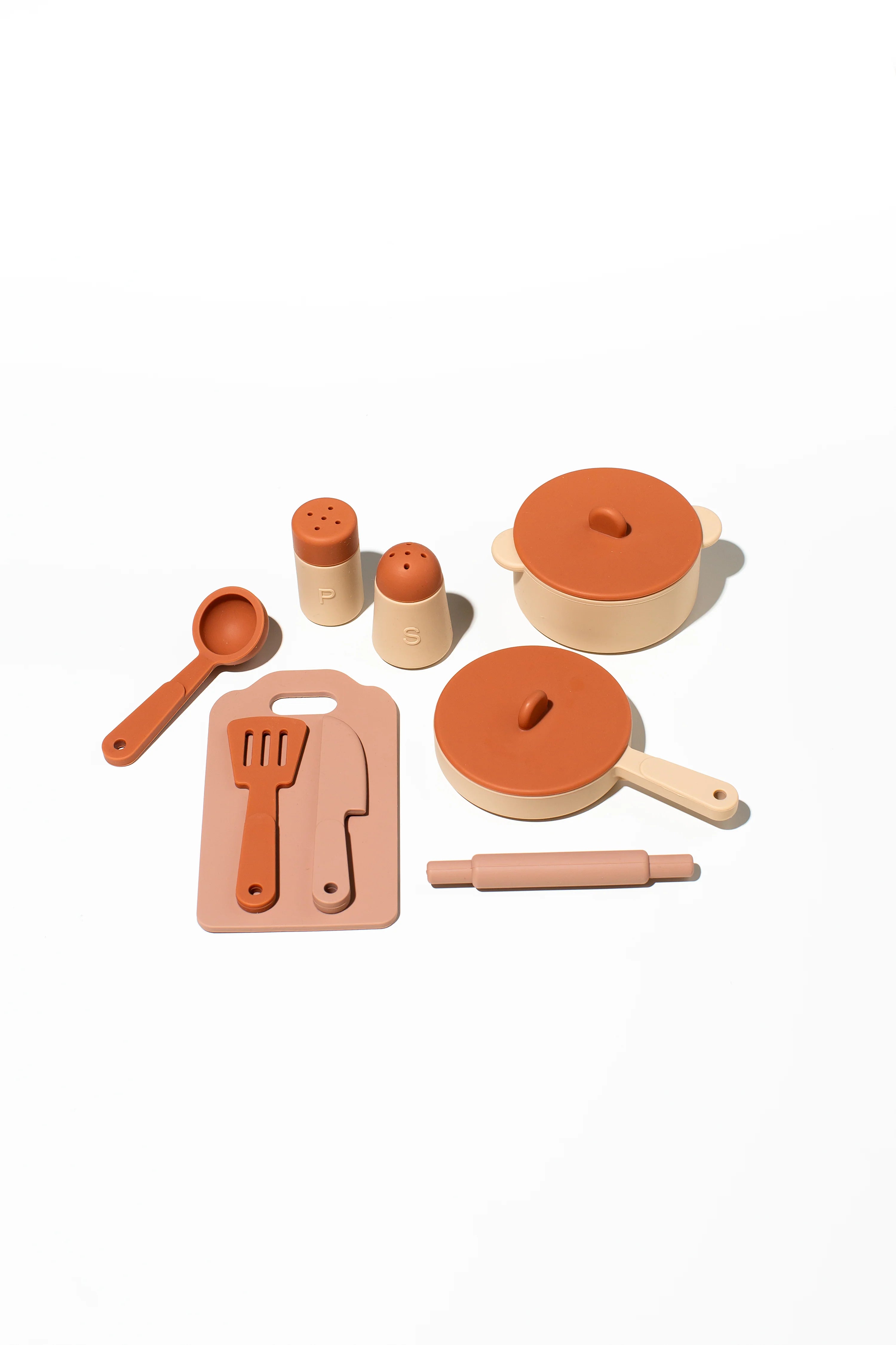 LITTLE DROP Cooking Set: This delightful collection features beige and orange plastic toy kitchen utensils and accessories, beautifully arranged on a white background. The set includes a small pot with a lid, a large pot with a lid, a cutting board, spatula, knife, measuring spoon, rolling pin, and two salt and pepper shakers—an ideal kit for nurturing children's culinary creativity.