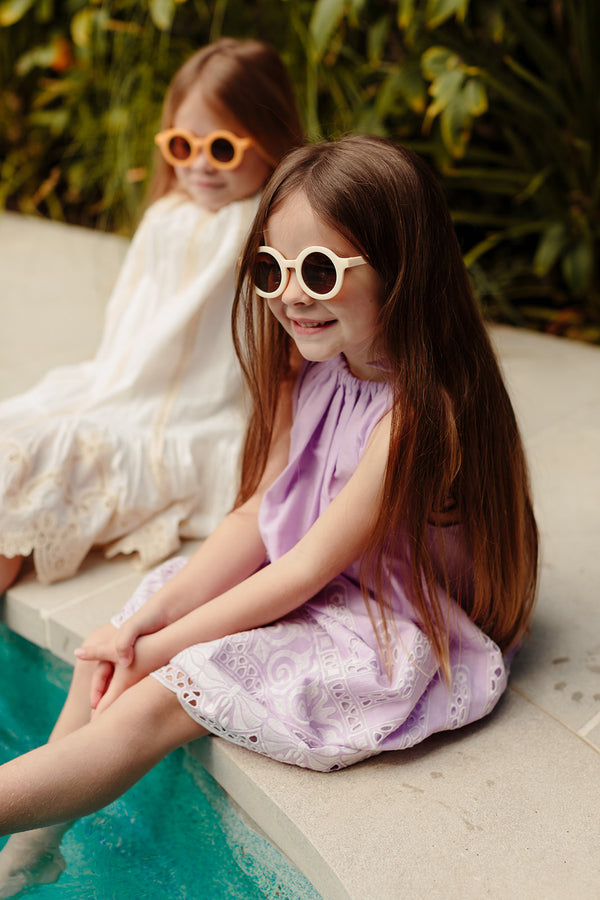 Two girls sitting by pool wearing sunglasses