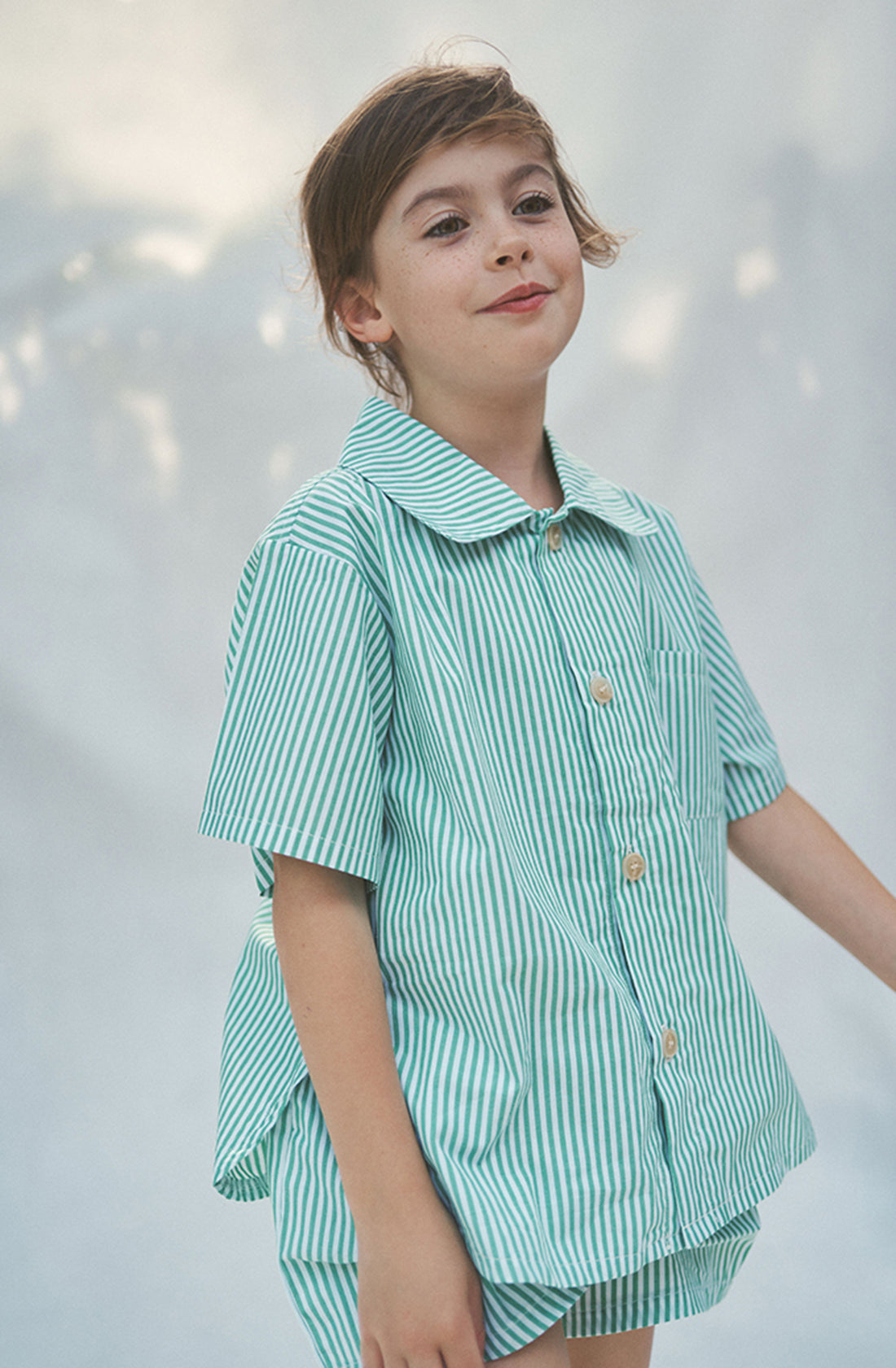 Brunette girl wearing the Alva Shirt and matching shorts against a white background