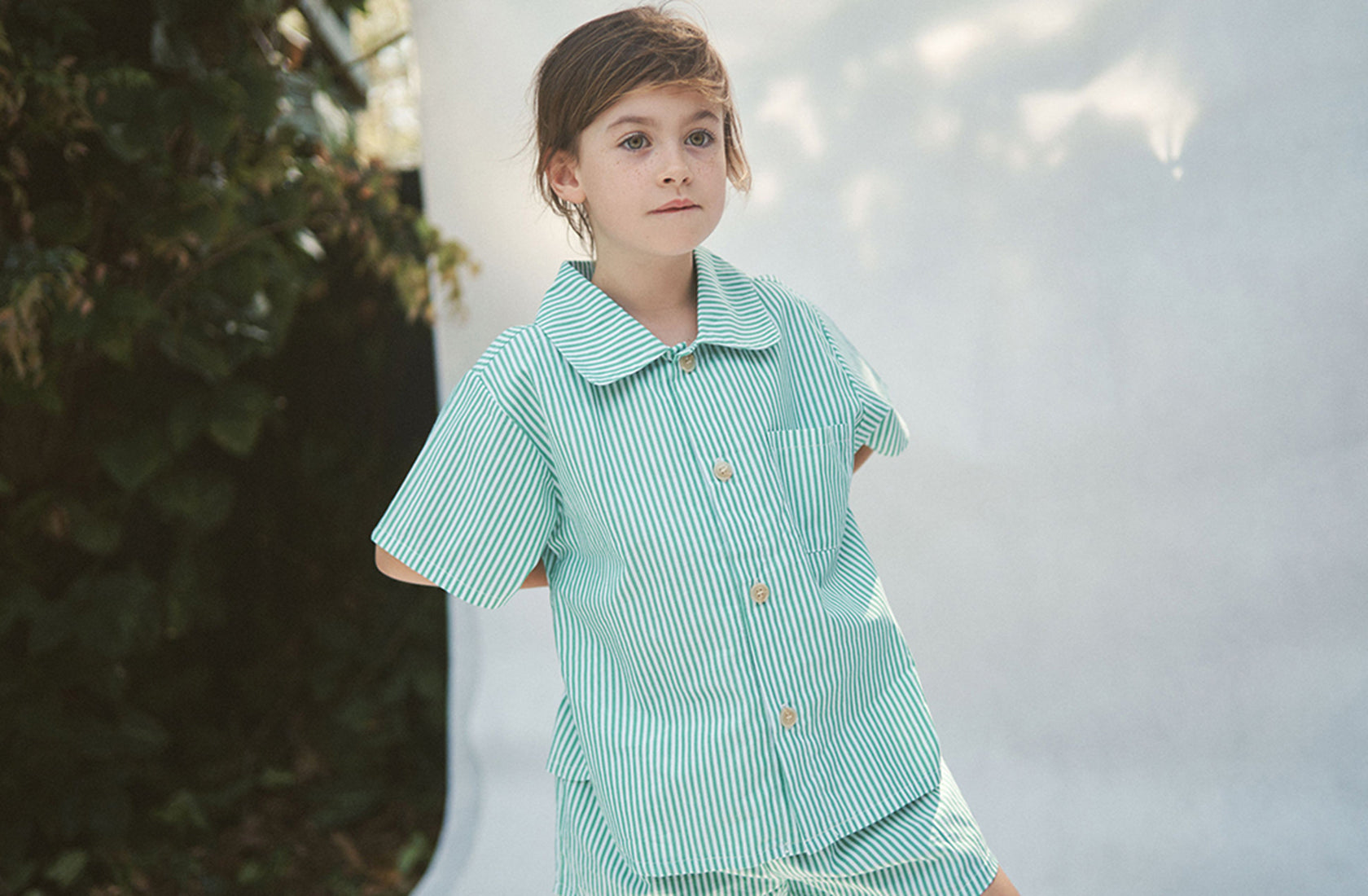 Brunette girl looking into the distance wearing the Alva shirt and short set against a white background