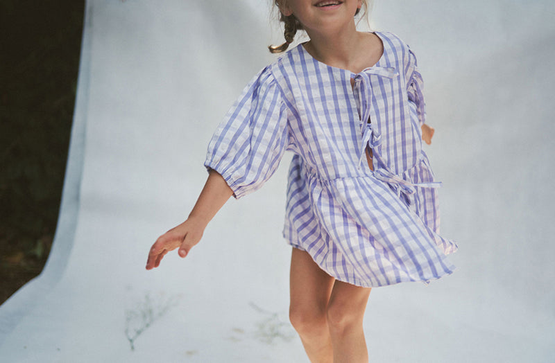 Close up of girl running towards the camera wearing the lilac gingham Cami blouse