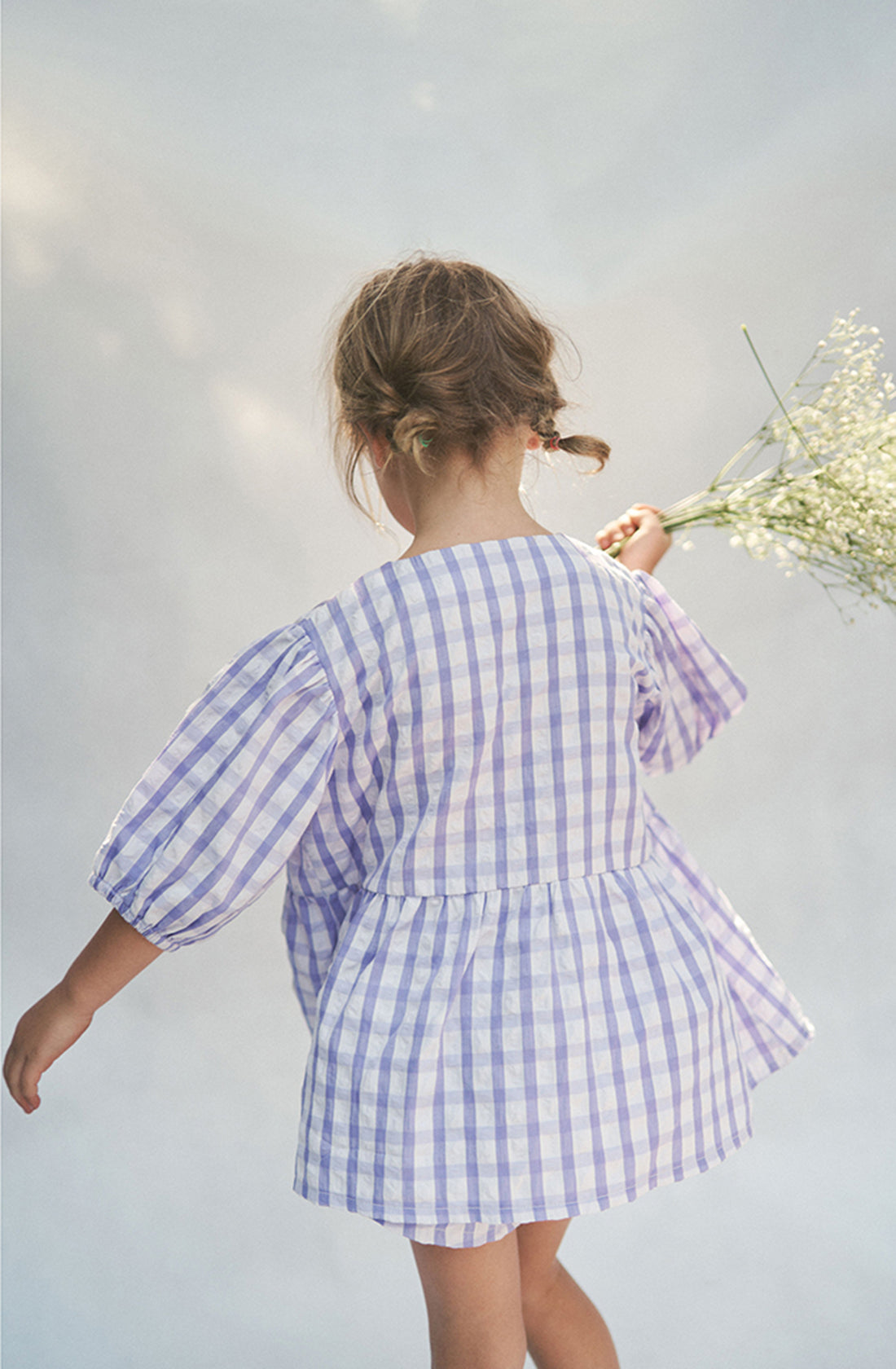 Rear view of blonde girl twirling while wearing the Cami Blouse