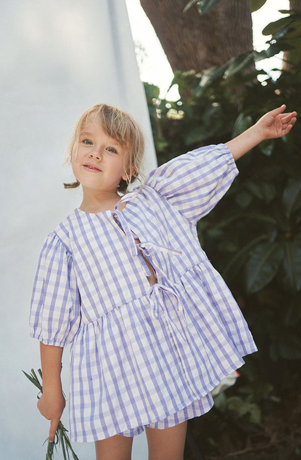 Blonde girl with raised arm wearing the lilac gingham Cami Blouse