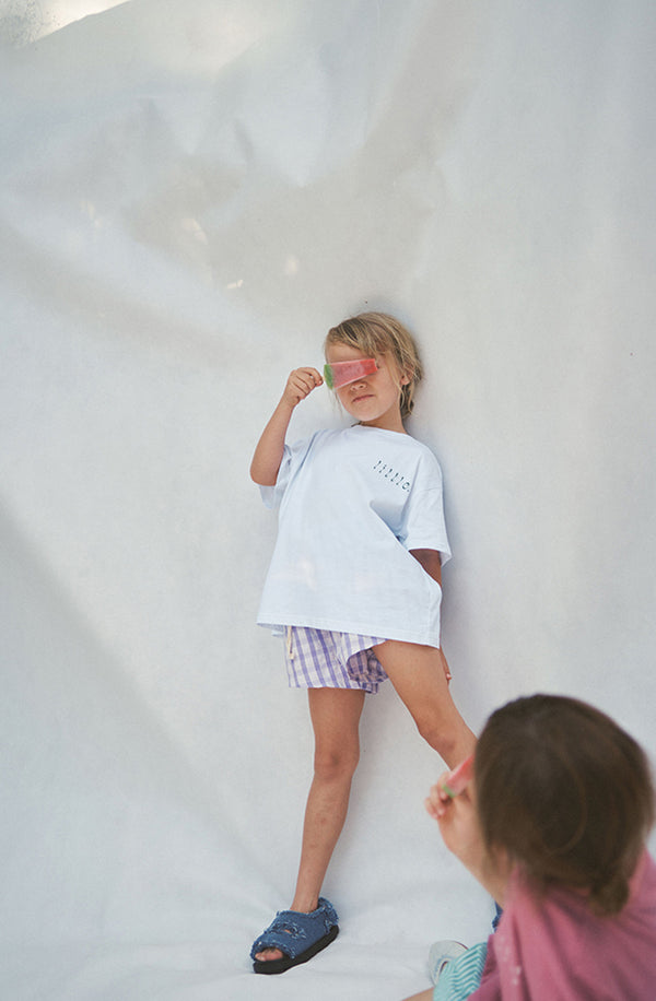 Girl hiding her face behind an icy pole wearing the Cami shorts with a white t-shirt