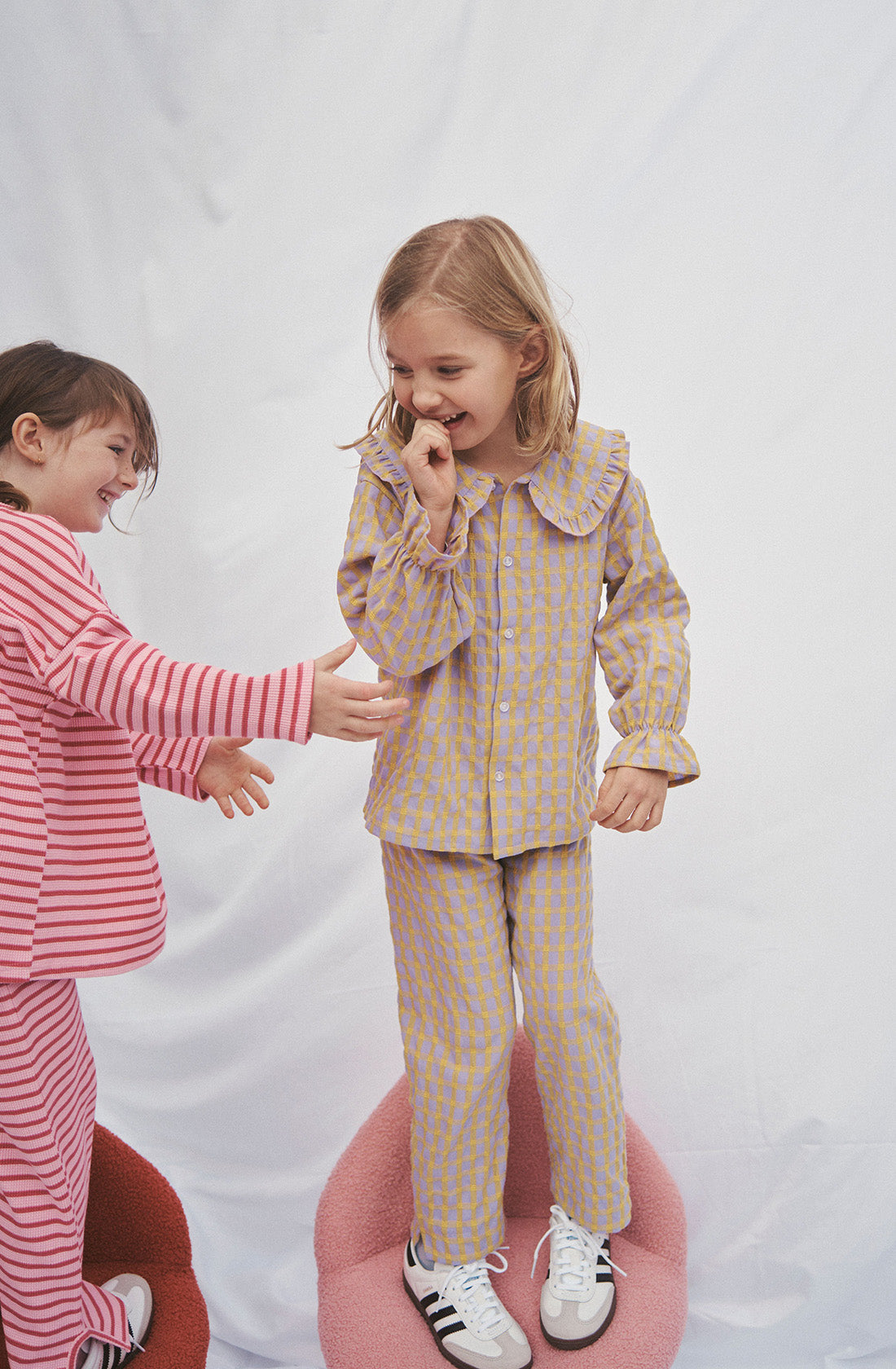 Young kid wearing the Maggie blouse l and matching pant standing on a chair.