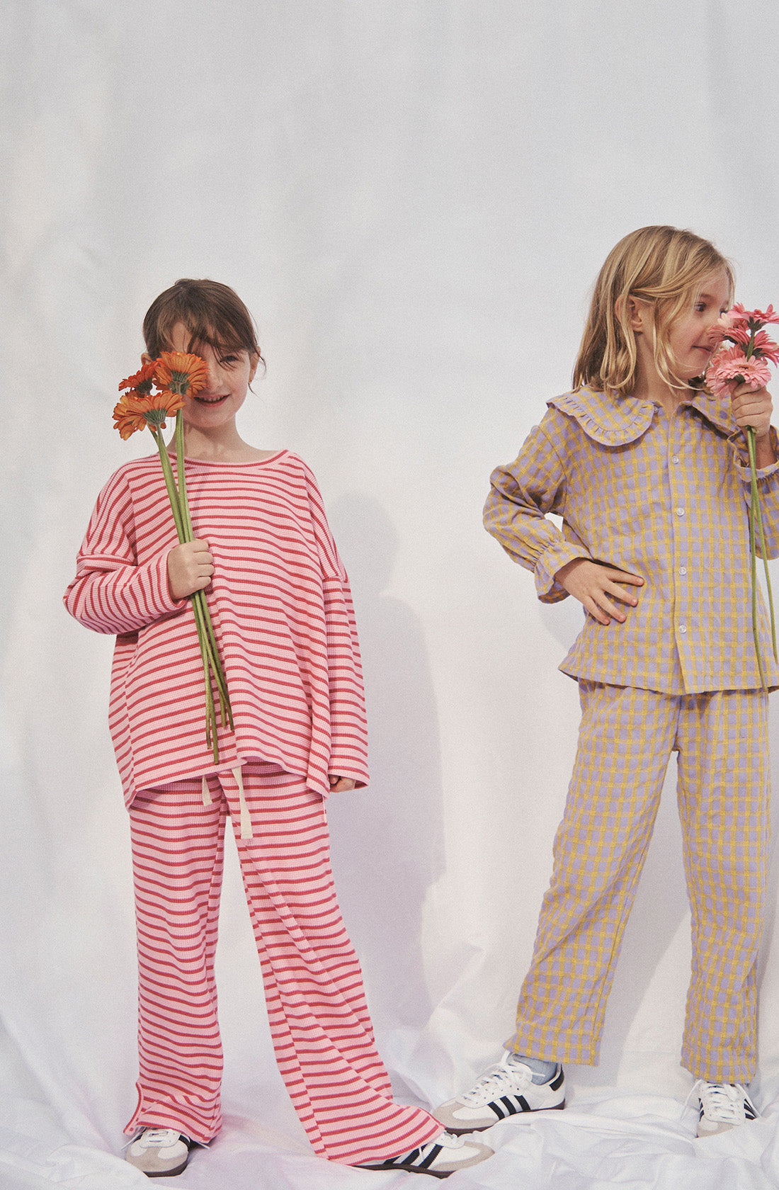 Young kid wearing the lucky lounge pant and matching top in candy apple holding a bunch of flowers in front of her face.