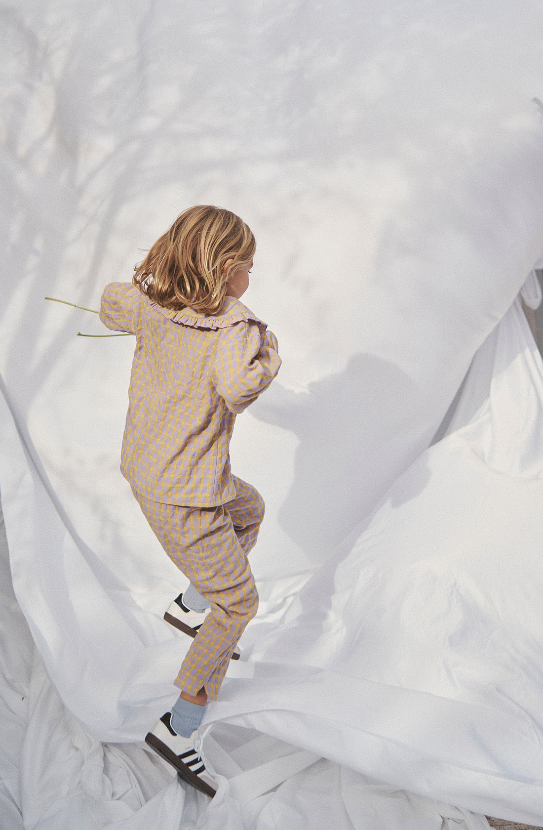 Young kid wearing the Maggie blouse l and matching pant jumping.