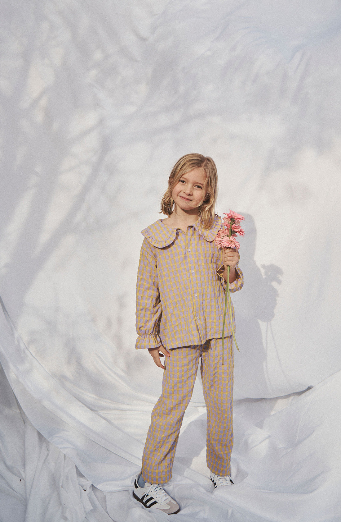 Young kid wearing the Maggie blouse l and matching pant holding flowers.