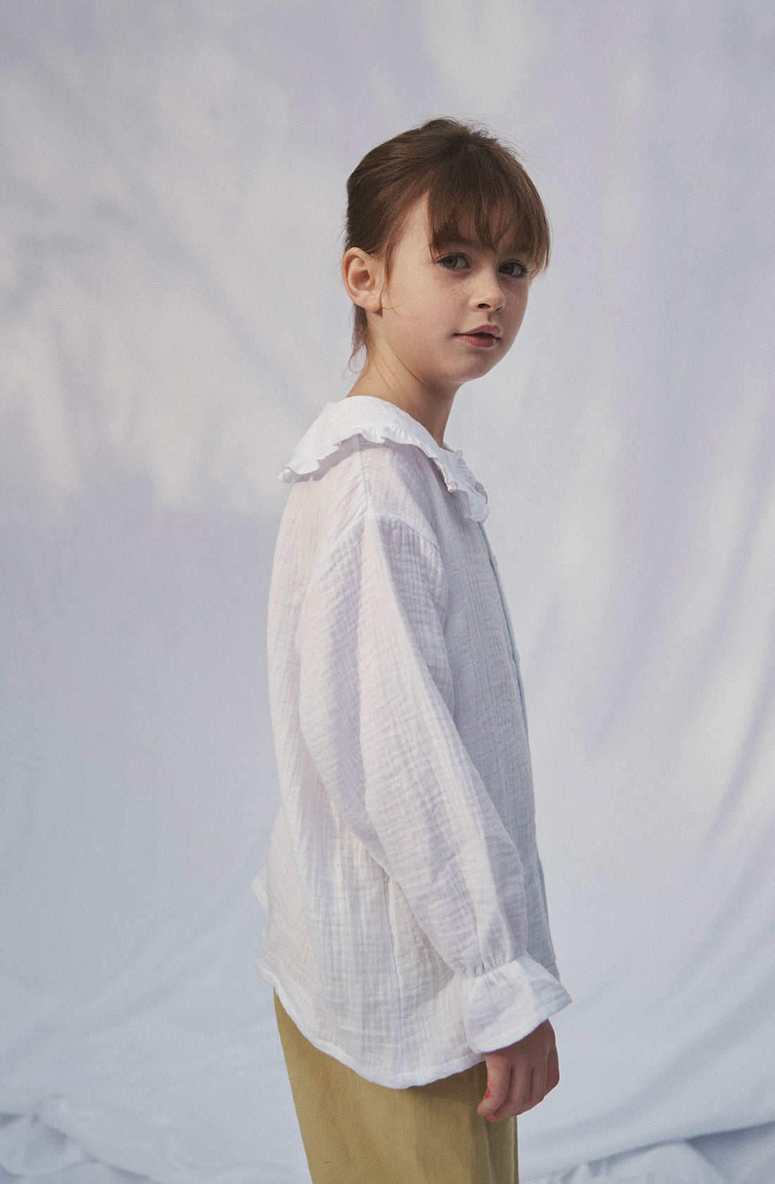 Young kid wearing the Maggie muslin blouse and mustard pants.