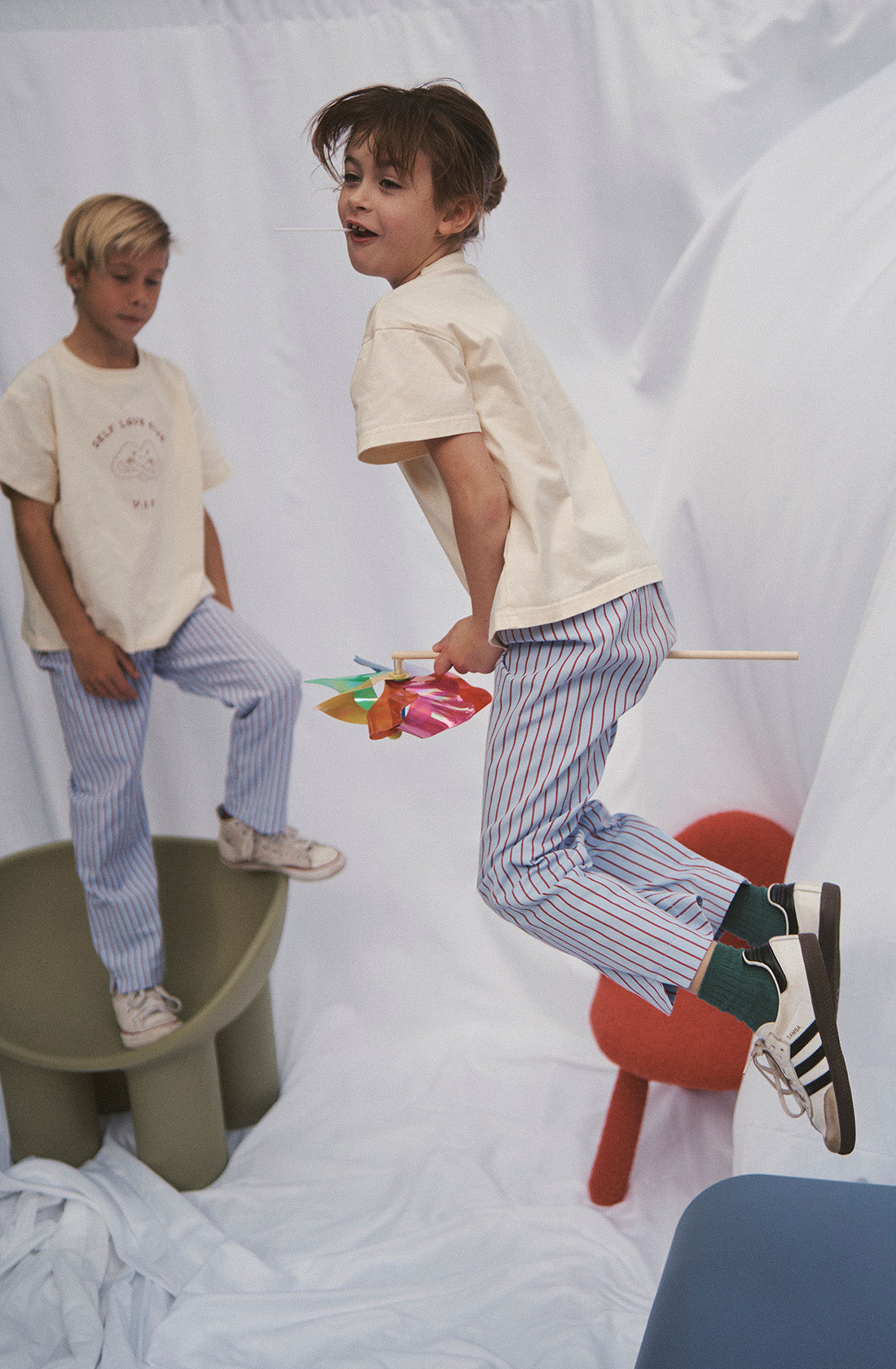 Two young kids wearing the party pant blue and red striped in a beige top.