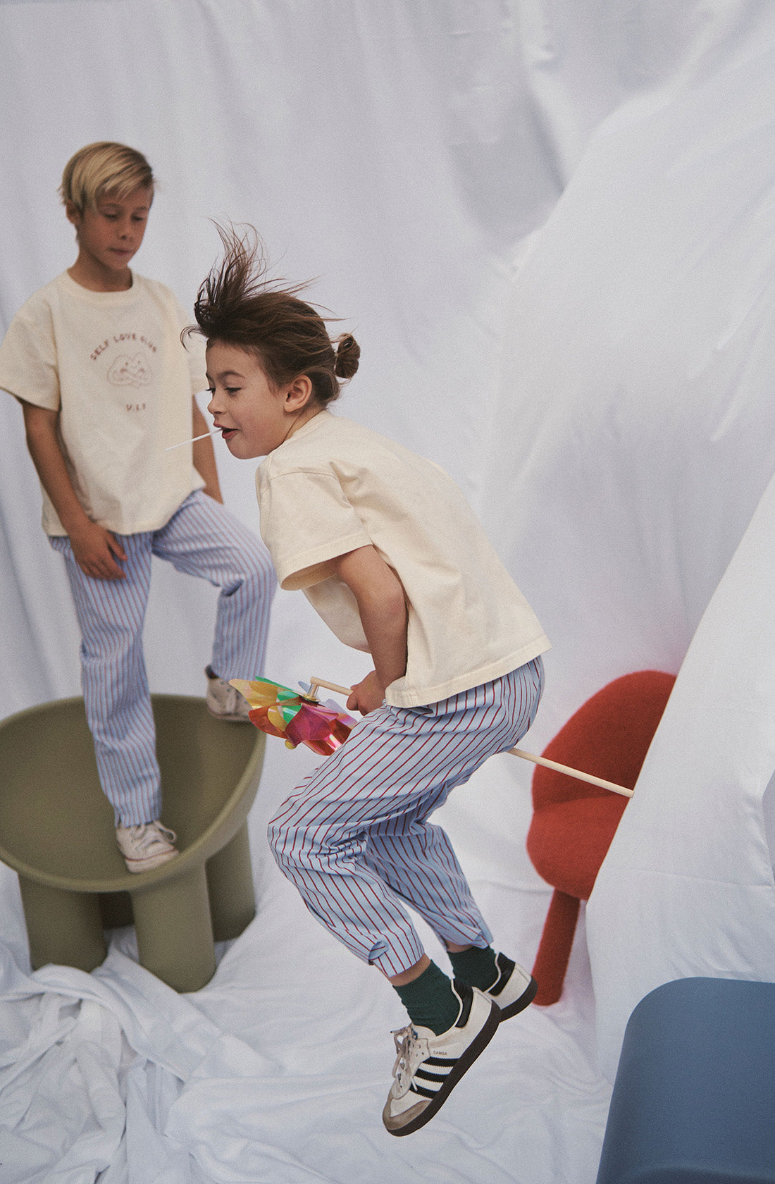 Two young kids wearing the party pant blue and red striped in a beige top.