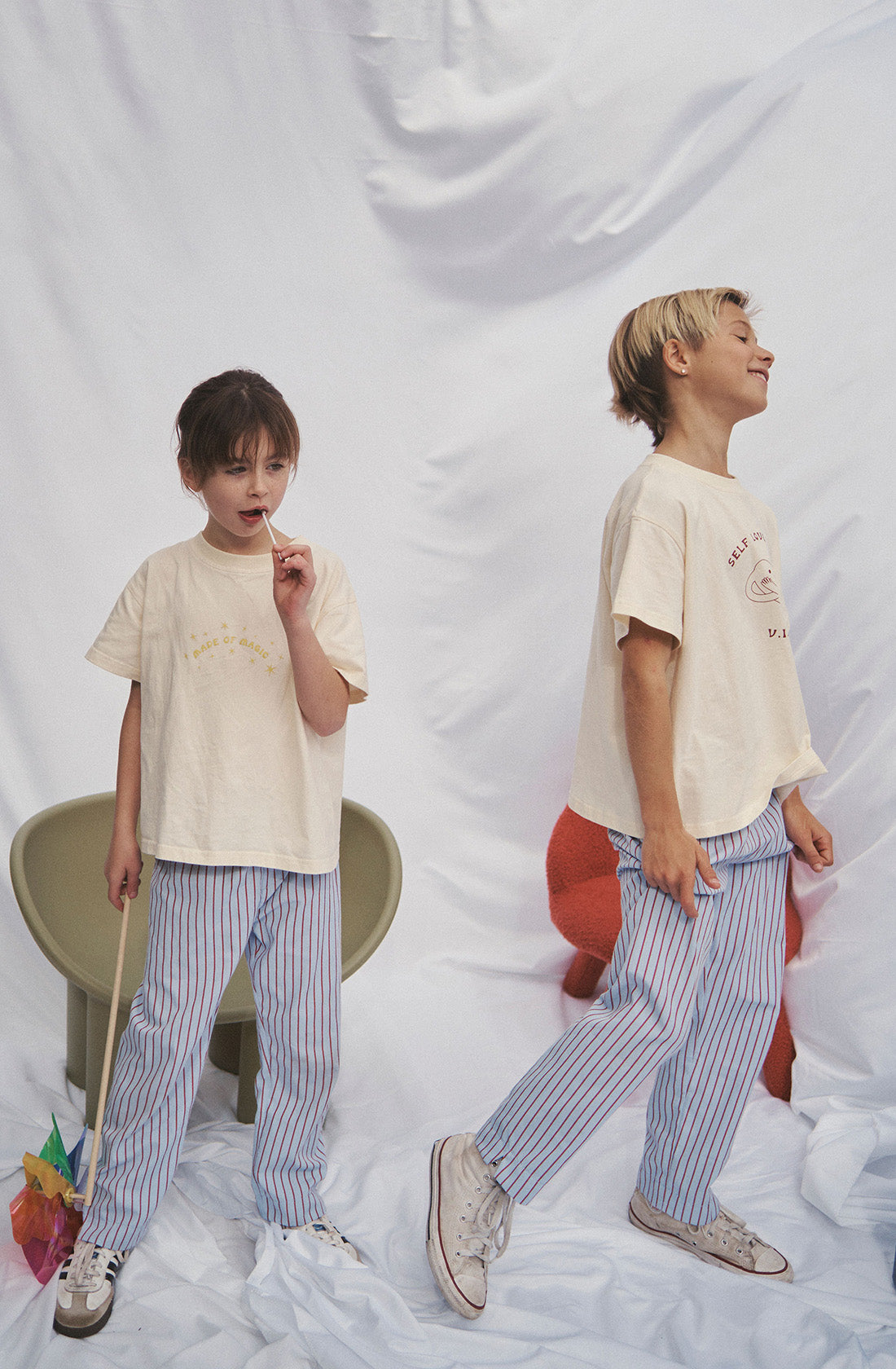 Two young kids wearing the party pant blue and red striped in a beige top.