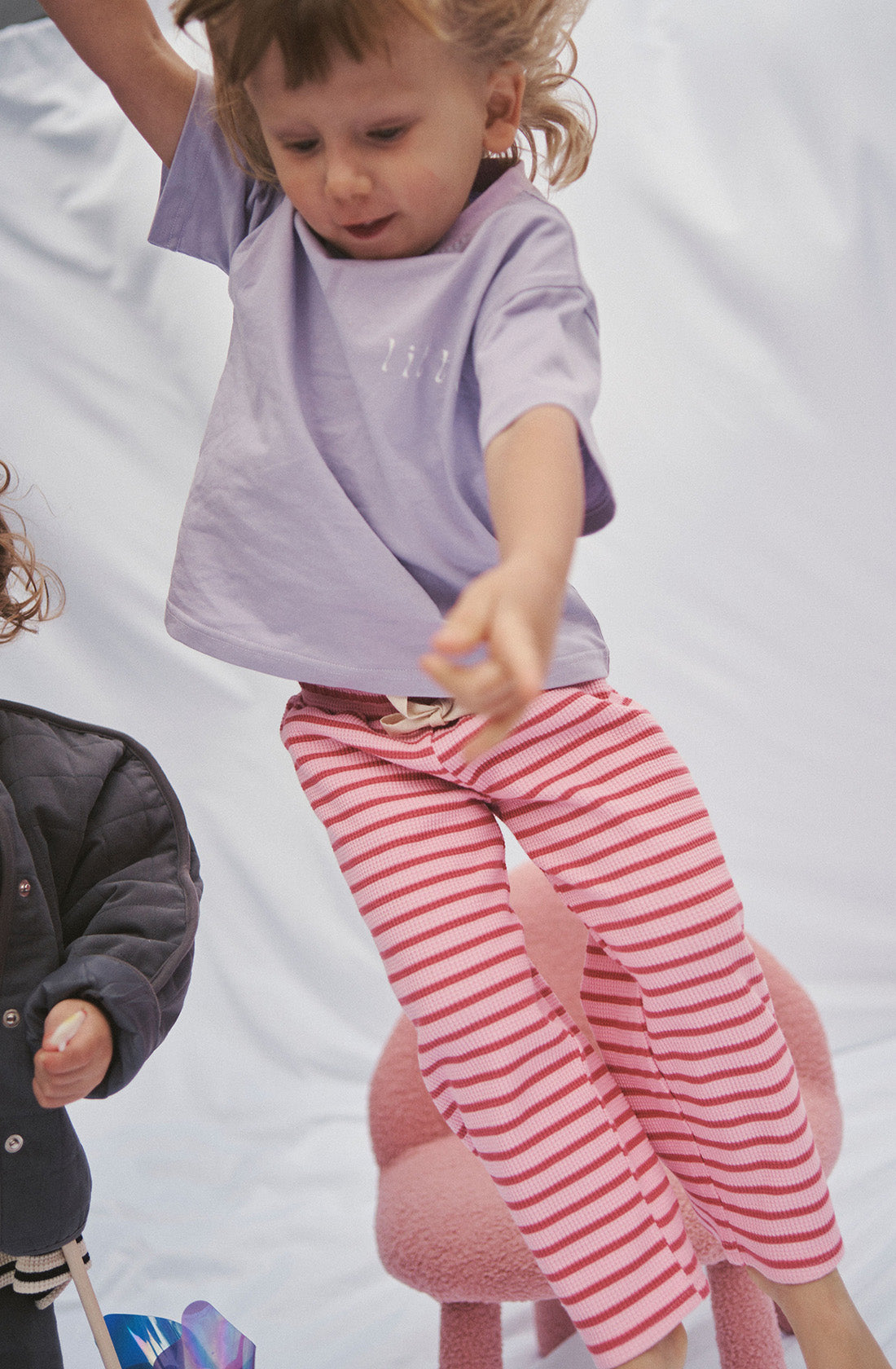 Young kid wearing the lucky lounge pant in candy apple with a purple top jumping in the air.