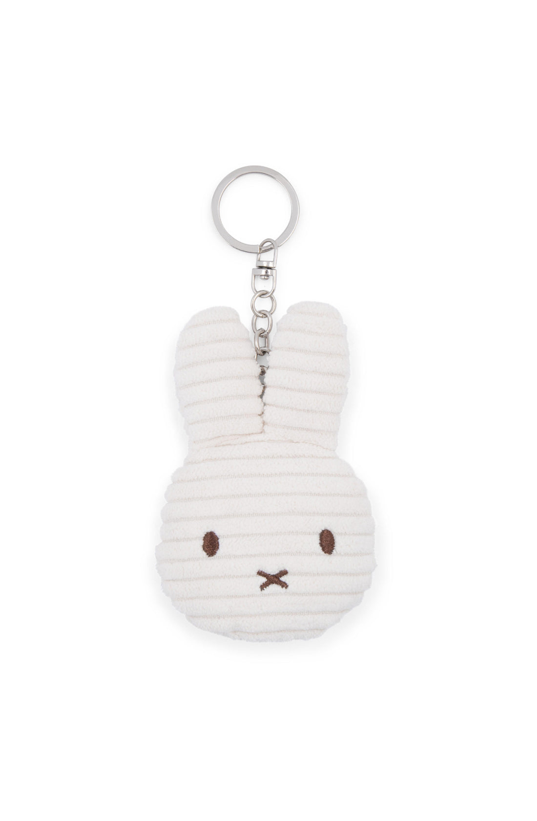 A close-up image of the BON TON TOYS X MIFFY "Miffy Flat Keychain Corduroy Off White," featuring a plush toy designed as a simple, white bunny head. The bunny features black stitched eyes, a small "X"-shaped nose and mouth, and a ribbed corduroy texture. Made from recycled polyester, it's the perfect backpack accessory with its attached silver keyring.