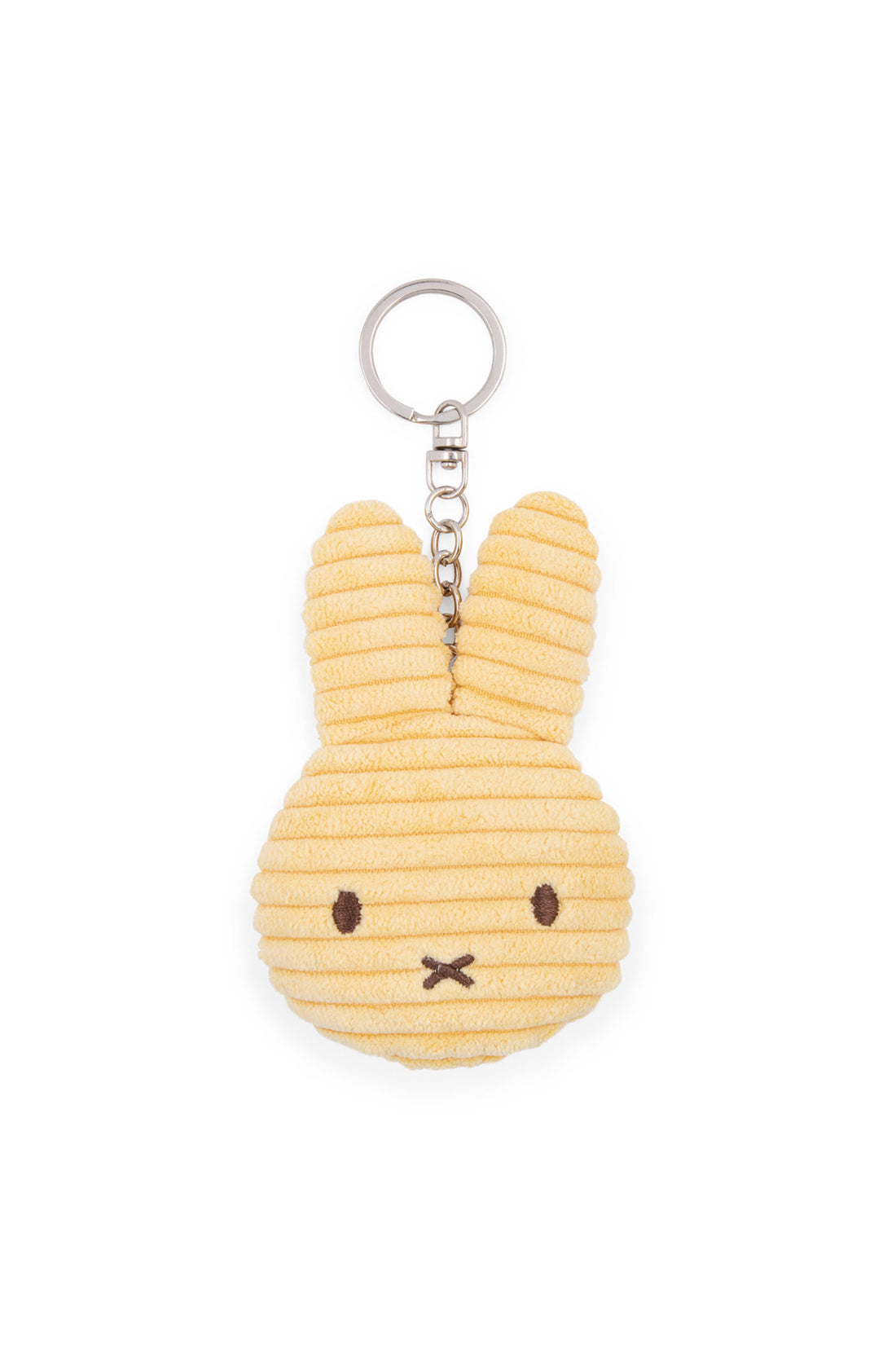 The Miffy Flat Keychain Corduroy Buttercream by BON TON TOYS X MIFFY features an adorable, textured yellow bunny head with long ears and a simple face, marked by two small black eyes and an X-shaped nose and mouth. This charming accessory, made from recycled polyester, is attached to a silver chain and keyring—perfect for your backpack.