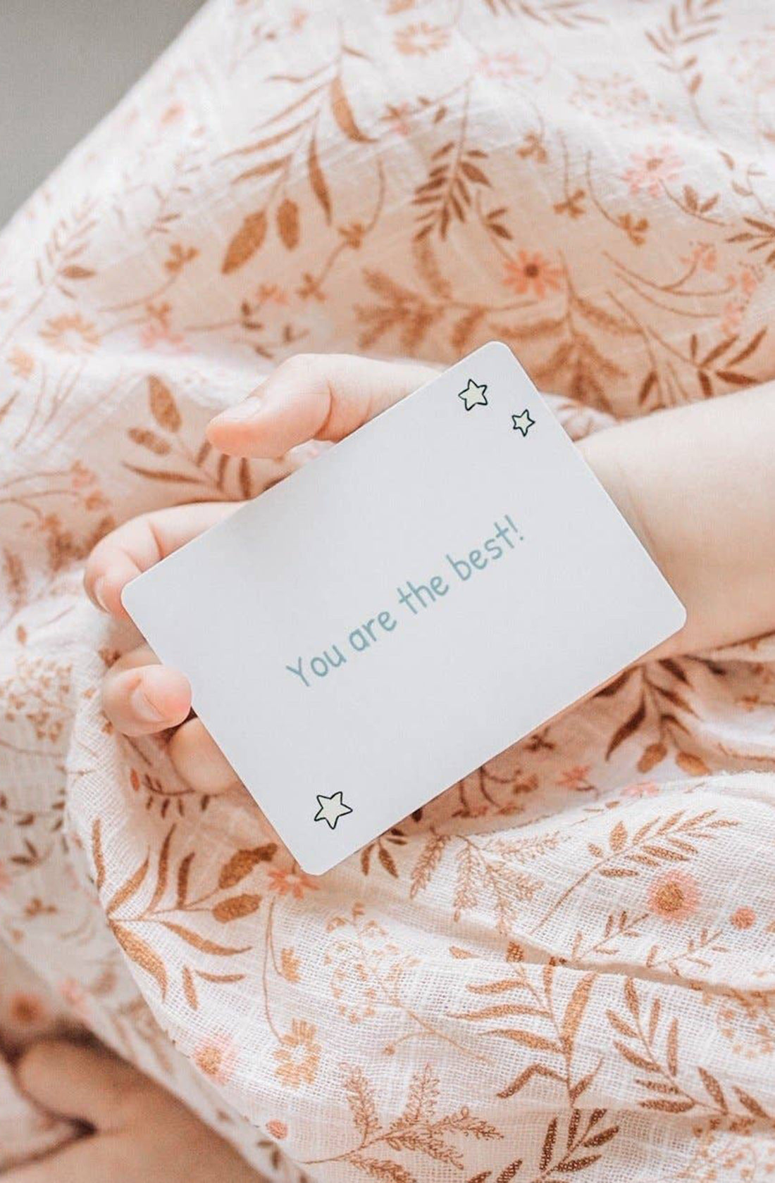 A young girl holding a card that says "you are the best" with three stars on it.