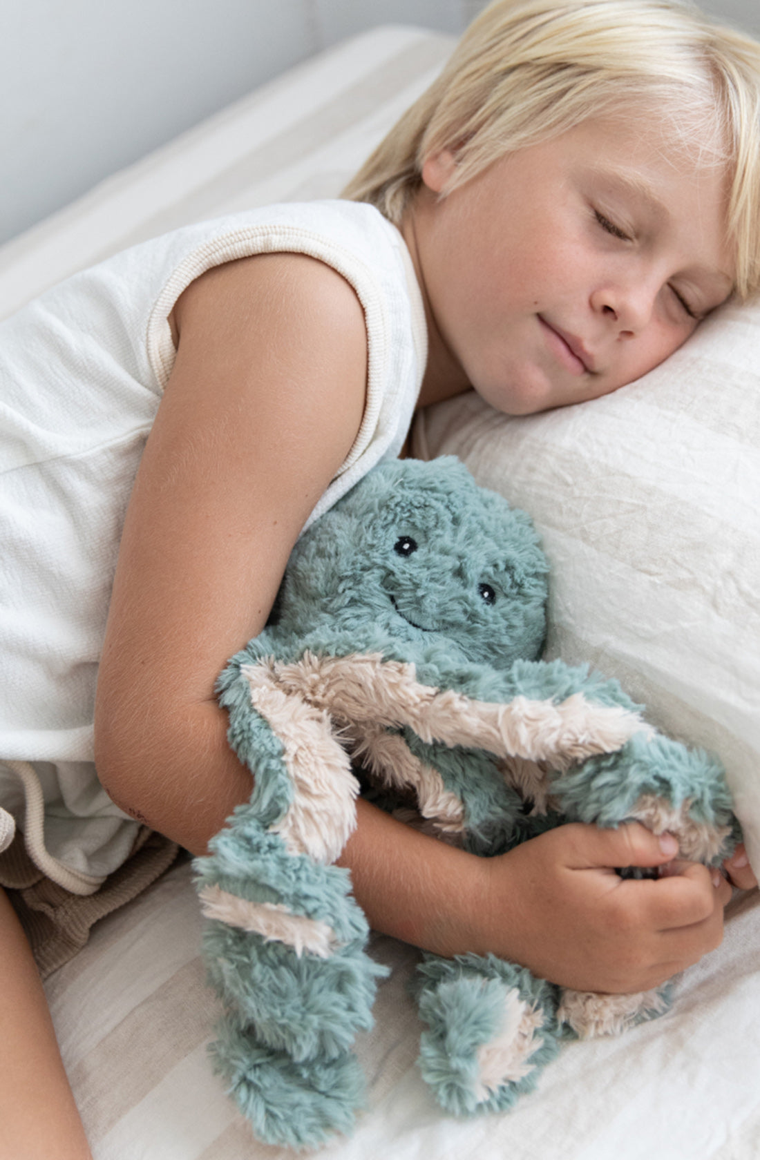 A young boy cuddling the weighted octopus toy.