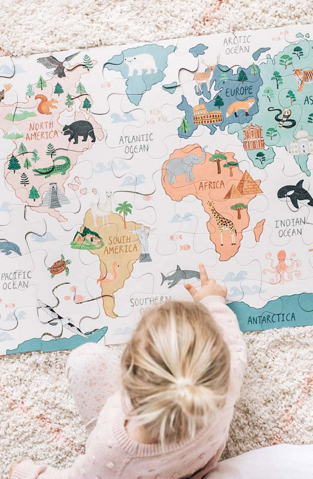 A girl playing with a world map puzzle. 