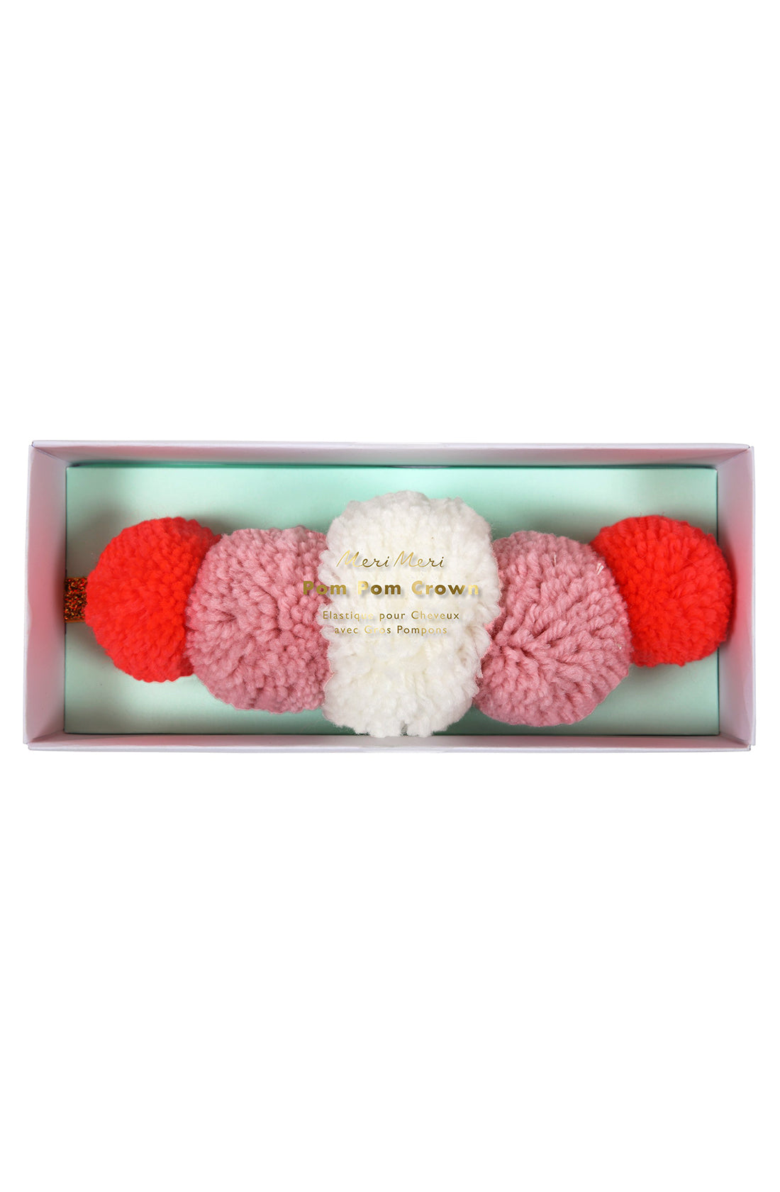 Image of the MERI MERI Pom Pom Crown headband in a rectangular box. The headband, perfect for any dressing-up costume, features large, fluffy pom-poms in shades of red, pink, and white. The box has a light blue interior and a clear lid with gold text.