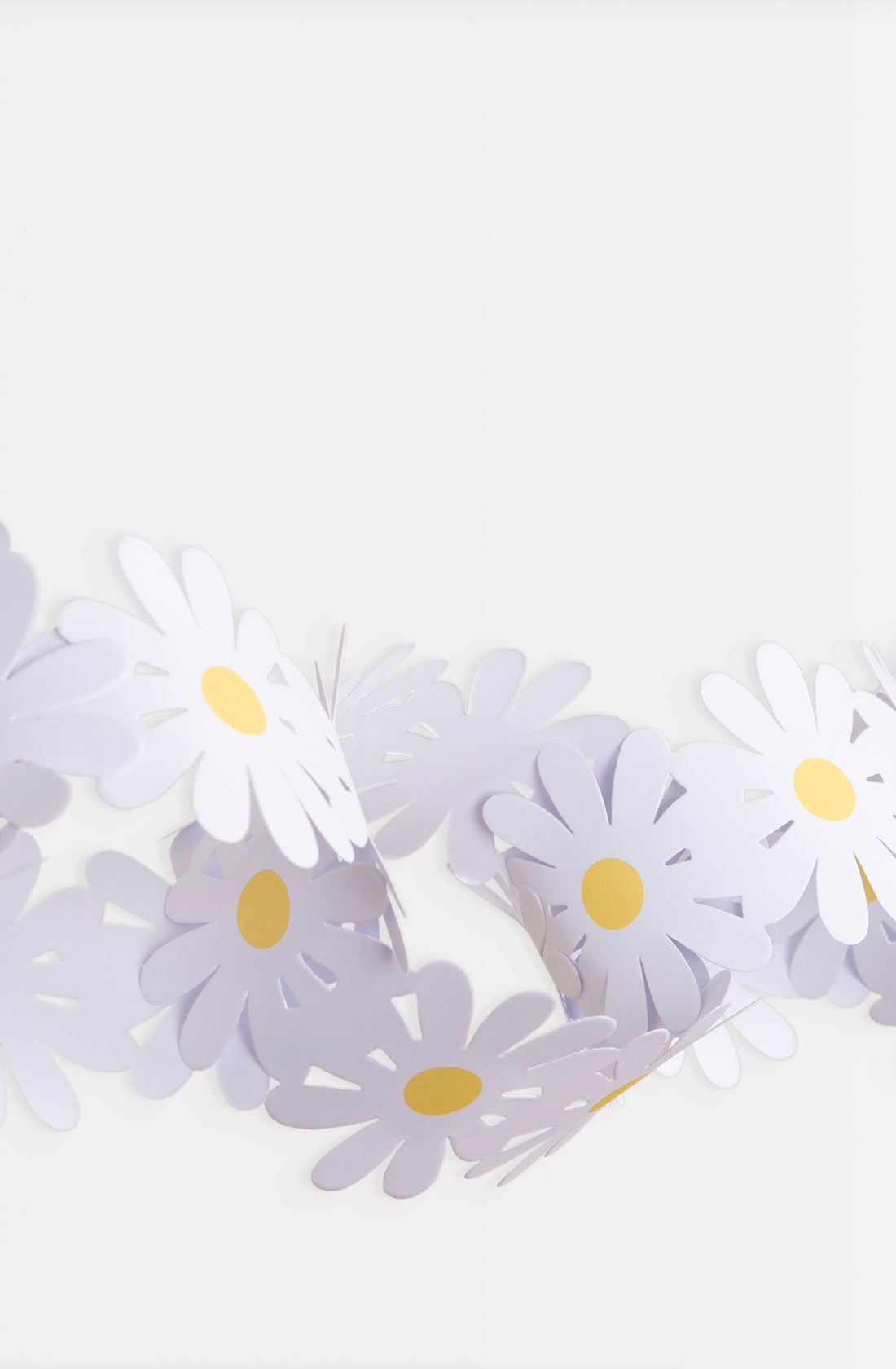 A decorative MERI MERI Daisy Paper Chain, featuring white flowers with yellow centers, is hanging against a plain white background. The daisies are arranged closely together, creating a festive and cheerful appearance that is perfect for Spring decorations.