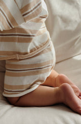 Baby kneeling on couch facing backwards wearing the stripe knit shorts in sand/chocolate