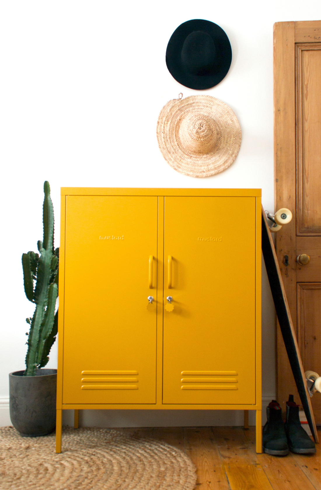 The midi locker in mustard next to cactus and skateboard.