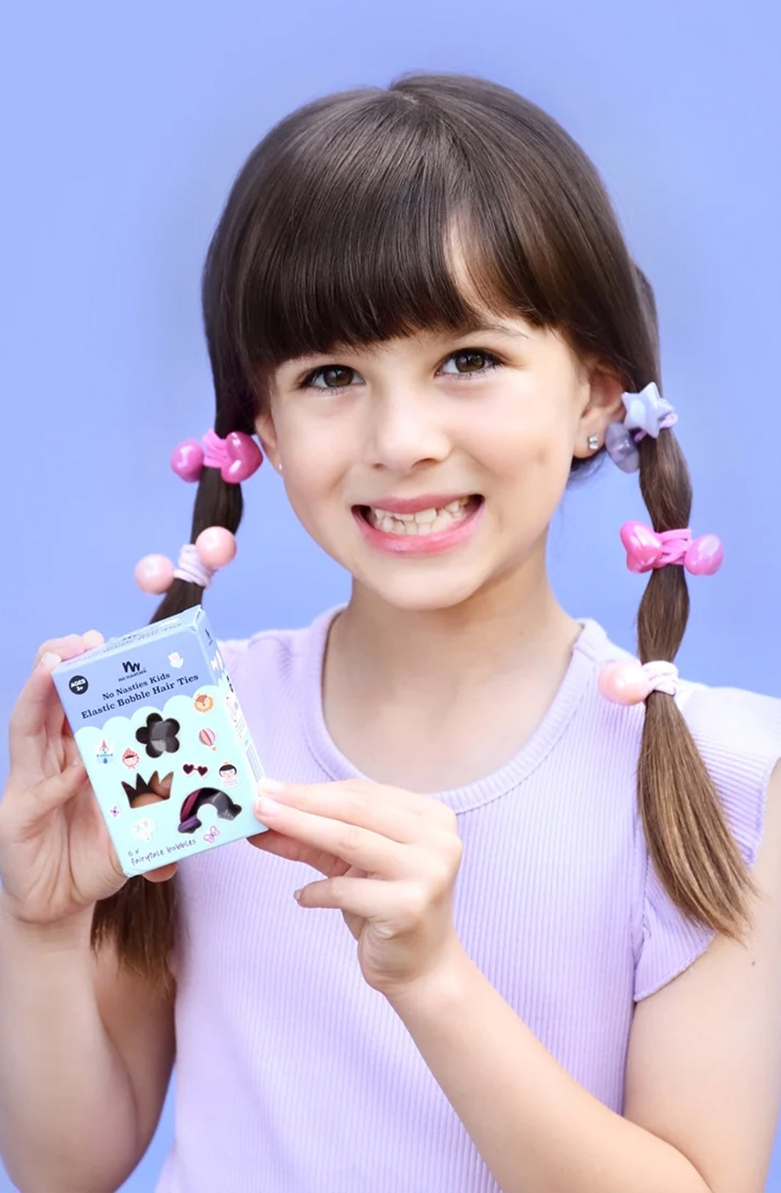 A young girl with the no nasties fairytale bobbles in them holding the packaging for them.