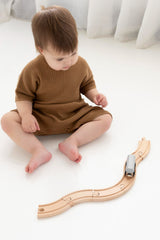 Baby playing with train set while wearing the slouchy rib knit romper in copper
