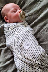 Baby with dummy wrapped in stretchy swaddle in Mini Stripe