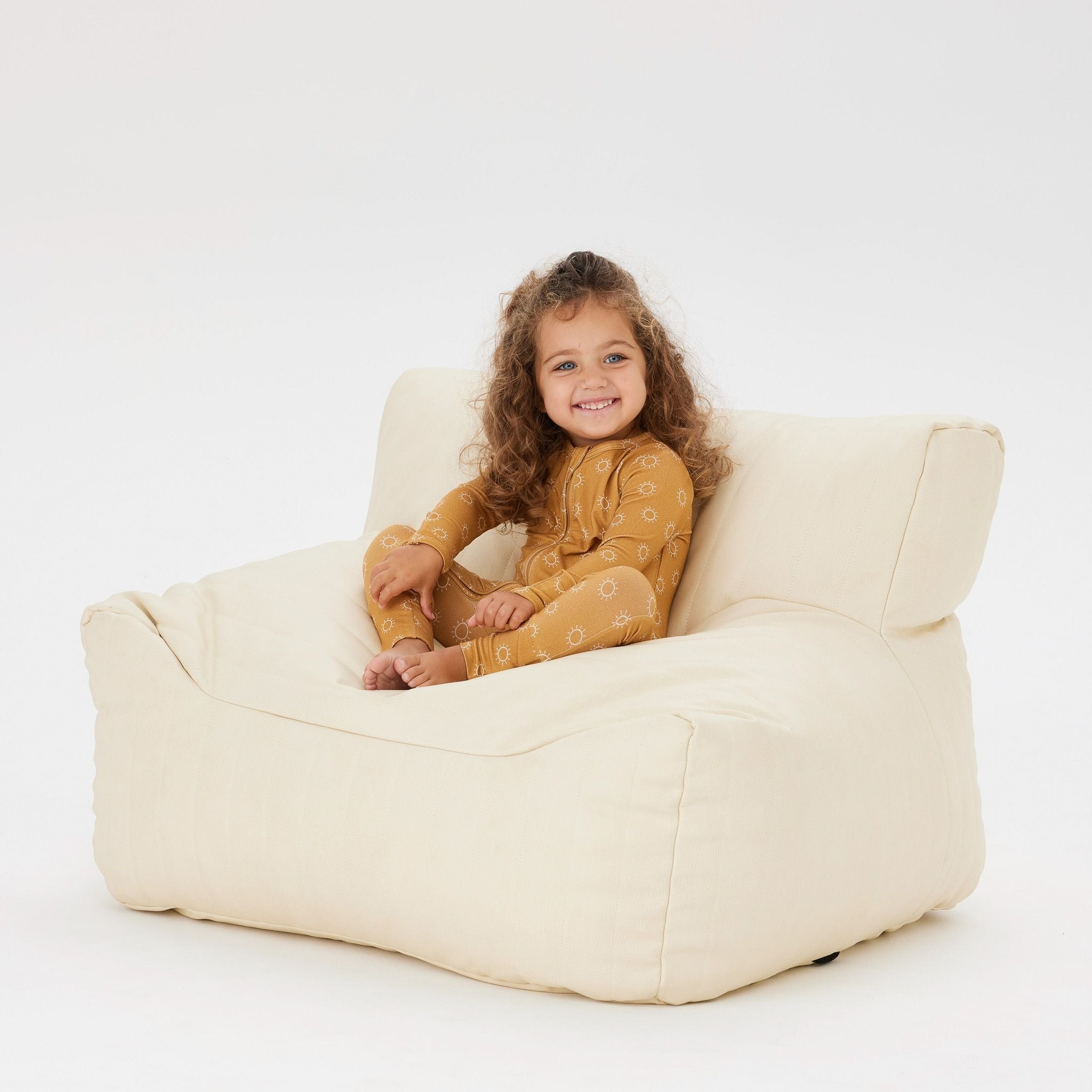 A Toddler wearing the Day or Night Onesies Sunrise sitting on a beanbag chair.