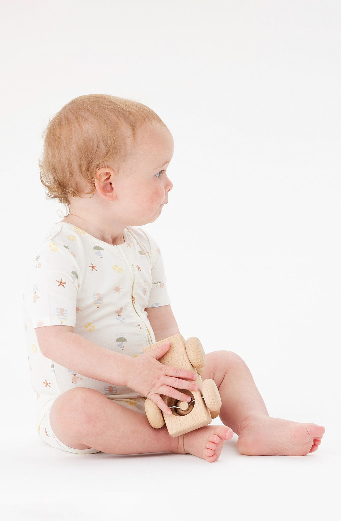 A Toddler wearing the Day or Night Short Sleeve Onesie Vacay playing with a toy.