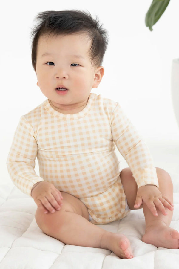 Sitting baby wearing the comfy bodysuit in neutral gingham