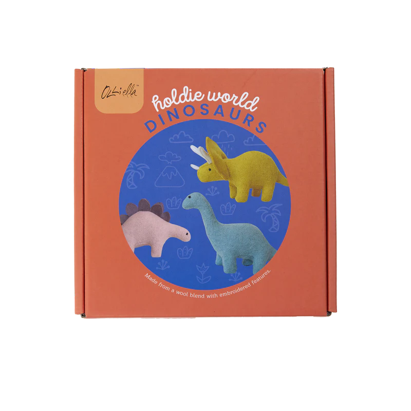 A square orange box labeled "Holdie Dinosaurs" from OLLI ELLA features three felt prehistoric pals: a yellow triceratops, a blue brachiosaurus, and a pink stegosaurus. Made from a handmade soft wool blend with embroidered features.