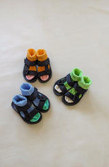 Three pairs of black sandals styled with brightly coloured socks
