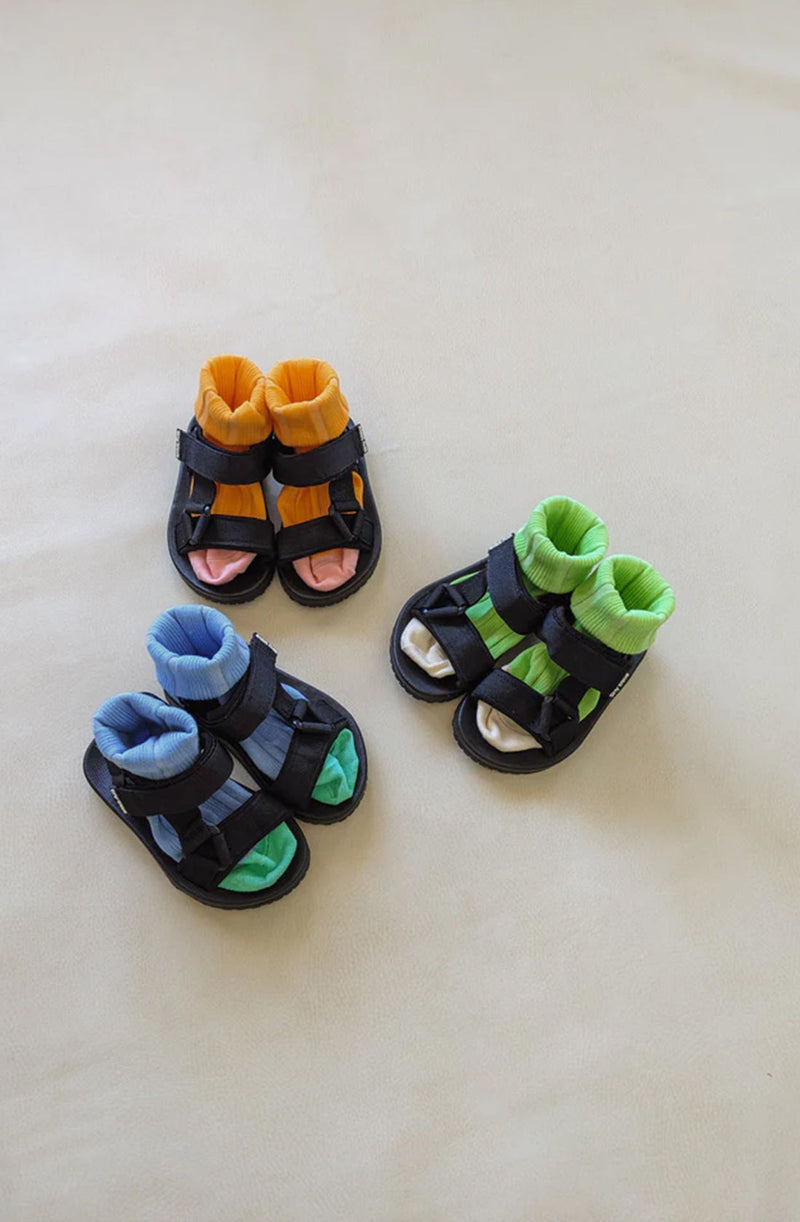 Three pairs of black sandals styled with brightly coloured socks