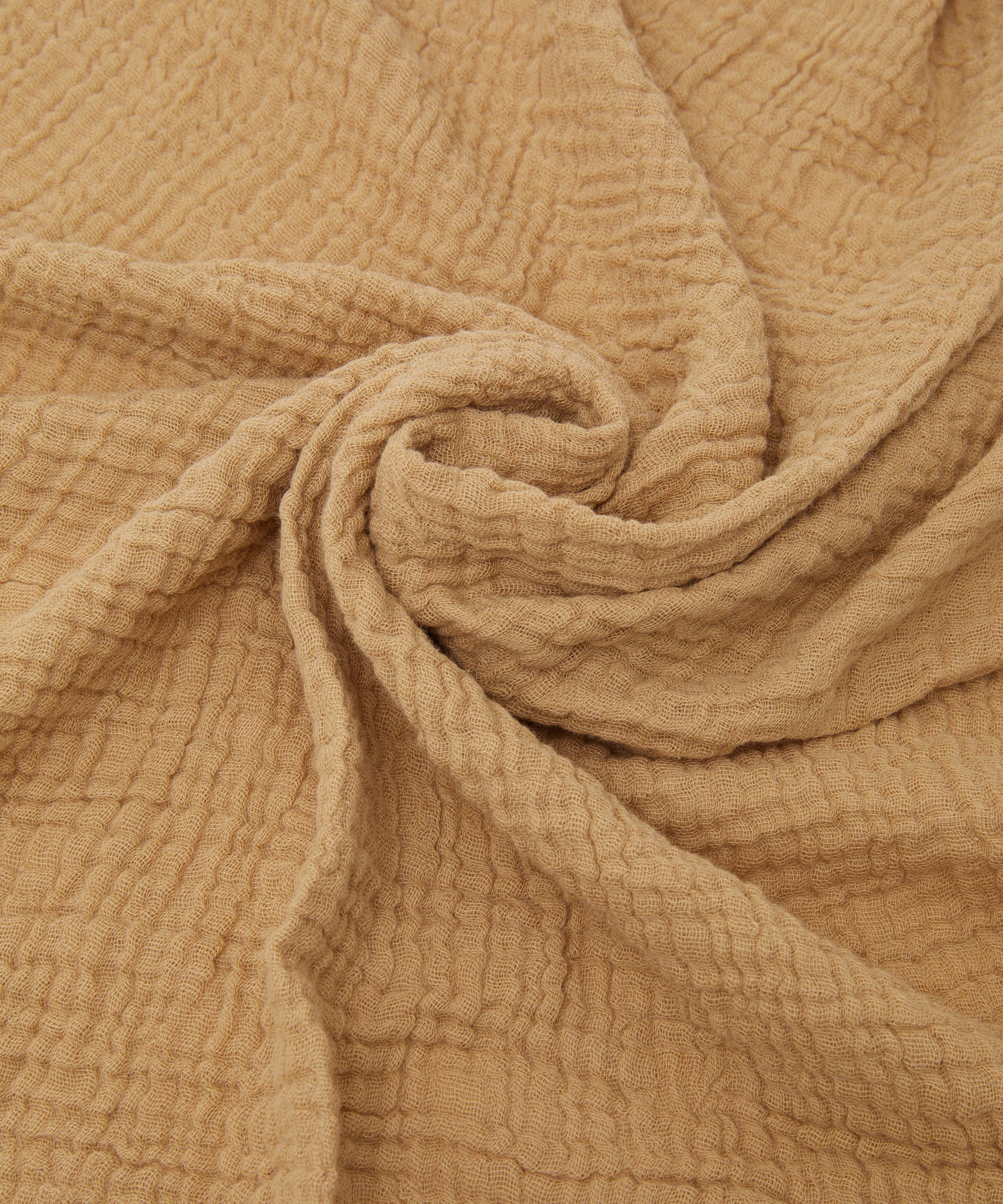 Close-up of crumpled beige fabric with a subtle checkered texture, creating swirling patterns and soft folds. From PHILÉ's Cotton Classics Collection, the Swaddle Cacao features Oeko-Tex Certified Cotton, ensuring comfort and quality for any extra-large muslin wrap or textile project.