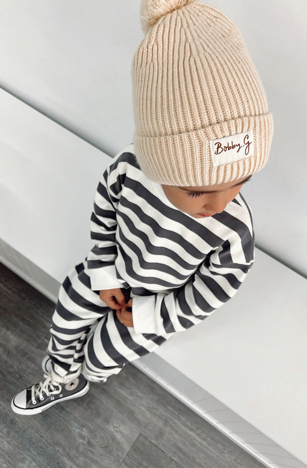 A young toddler wearing the Camden navy striped pullover and matching pants with the Bobby G cream beanie. The shot is taken from above the boys head.