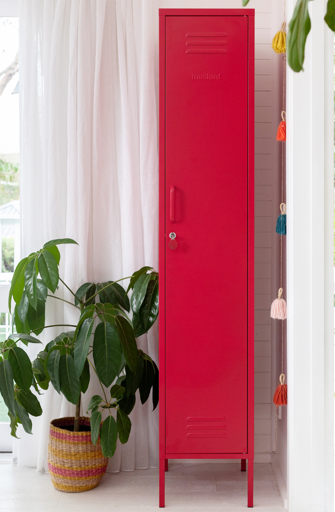 The skinny locker in poppy next to a pot plant.