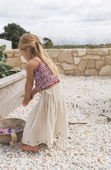 Girl playing in the garden while wearing the Posie skirt with shirred crop in red gingham.