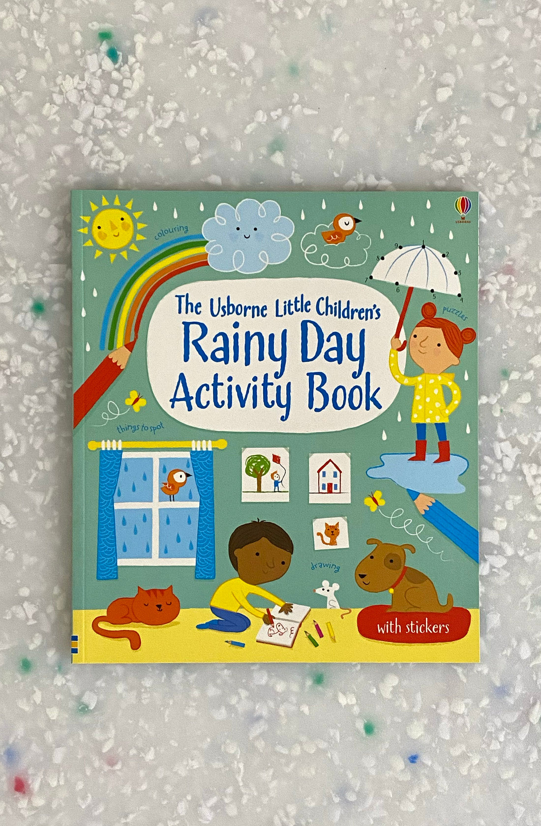 The Little Children's Rainy Day Activity Book by BAY KIDS is an interactive sticker book filled with delightful illustrations of children playing with arts and crafts indoors, a child with an umbrella, a rainbow, cute animal scenes puzzles, houses, trees, and a frog in the rain.