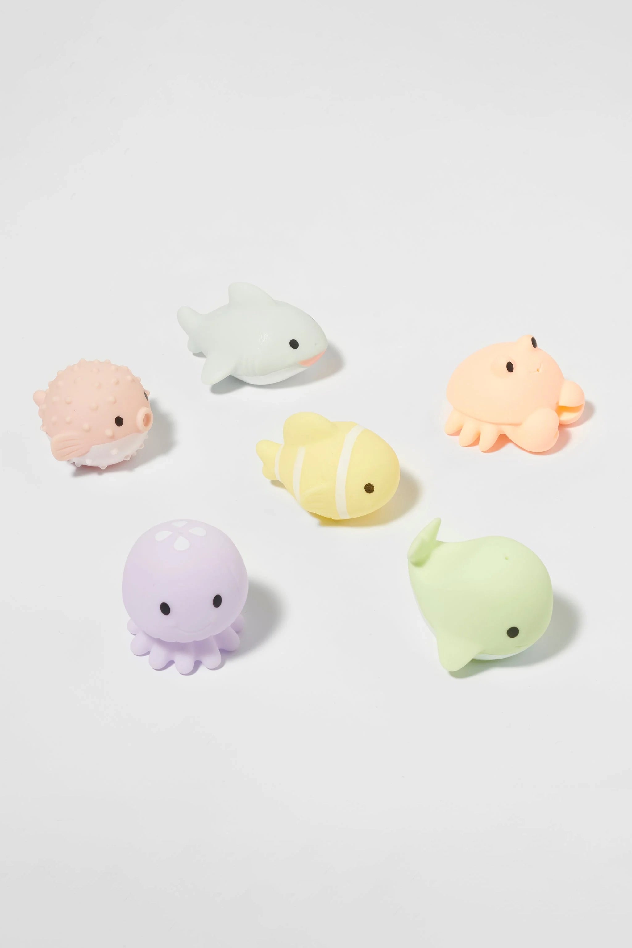 A collection of SUNNYLIFE's Sea Animal Splash Toys, featuring six pastel-colored bath toys shaped like sea creatures, arranged on a white surface. The set includes a pufferfish, shark, crab, octopus, clownfish, and whale—each with an adorable design and vibrant yet soft colors that are perfect for splash play and floating fun.