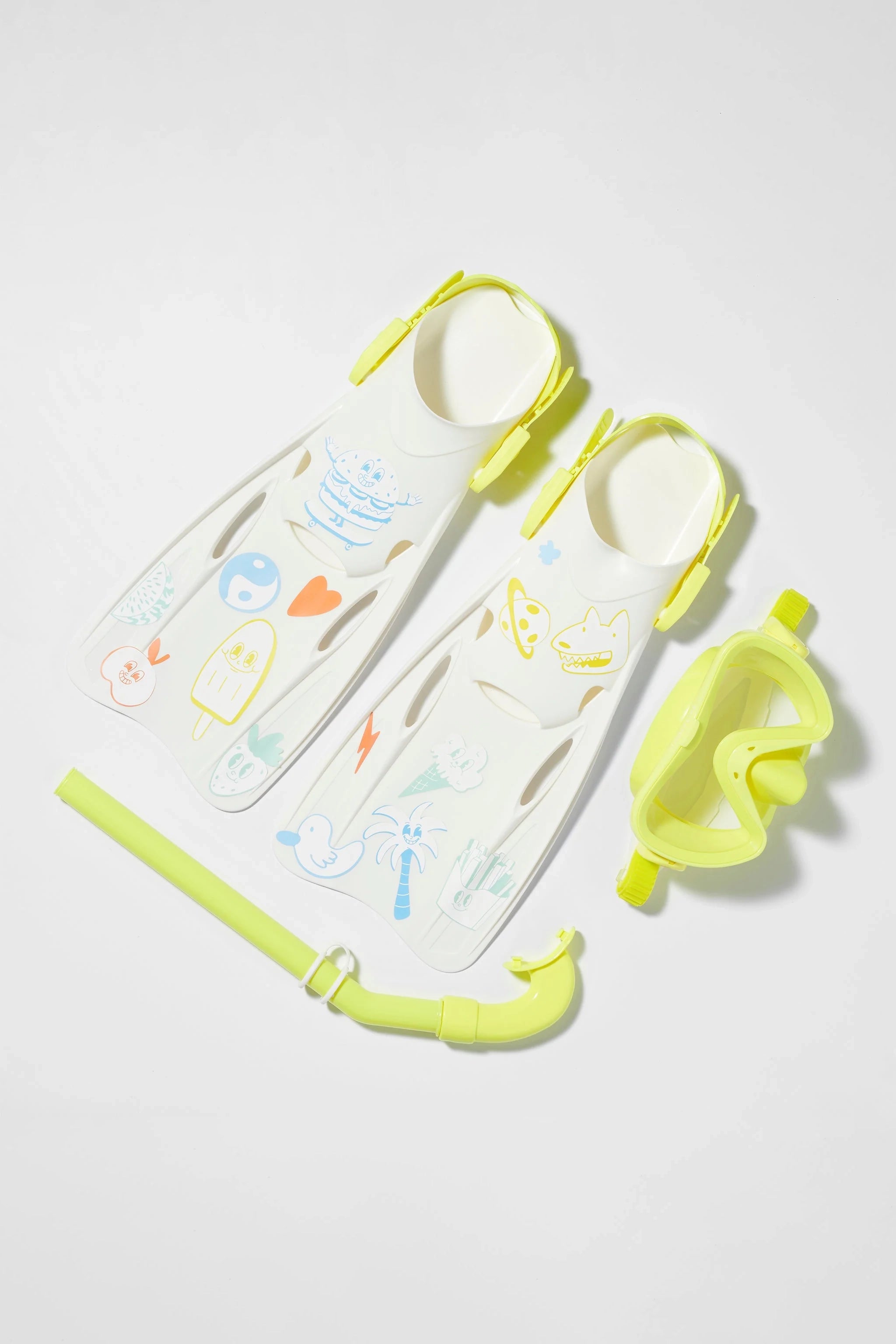 A set of light yellow snorkeling gear from SUNNYLIFE, including a pair of flippers adorned with playful, colorful cartoon illustrations, a matching snorkel mask, and a snorkel tube. The Kids Snorkel Set Yellow is placed on a white background.