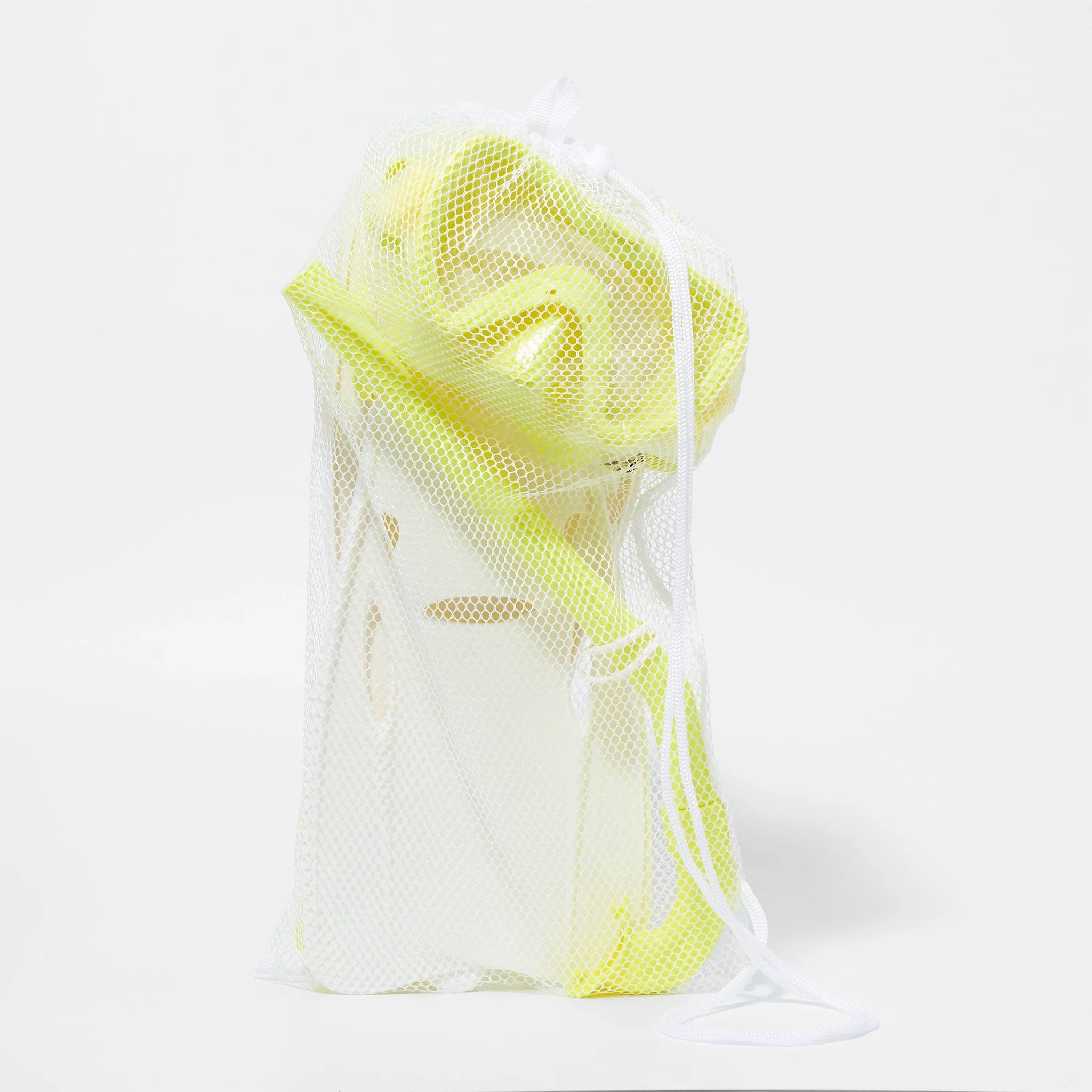 A white mesh laundry bag contains items from the Kids Snorkel Set Yellow by SUNNYLIFE, including a bright yellow snorkel and other yellow and white pieces. The bag is secured with a white drawstring, allowing the partially visible contents to show through the mesh fabric. The background is plain white.