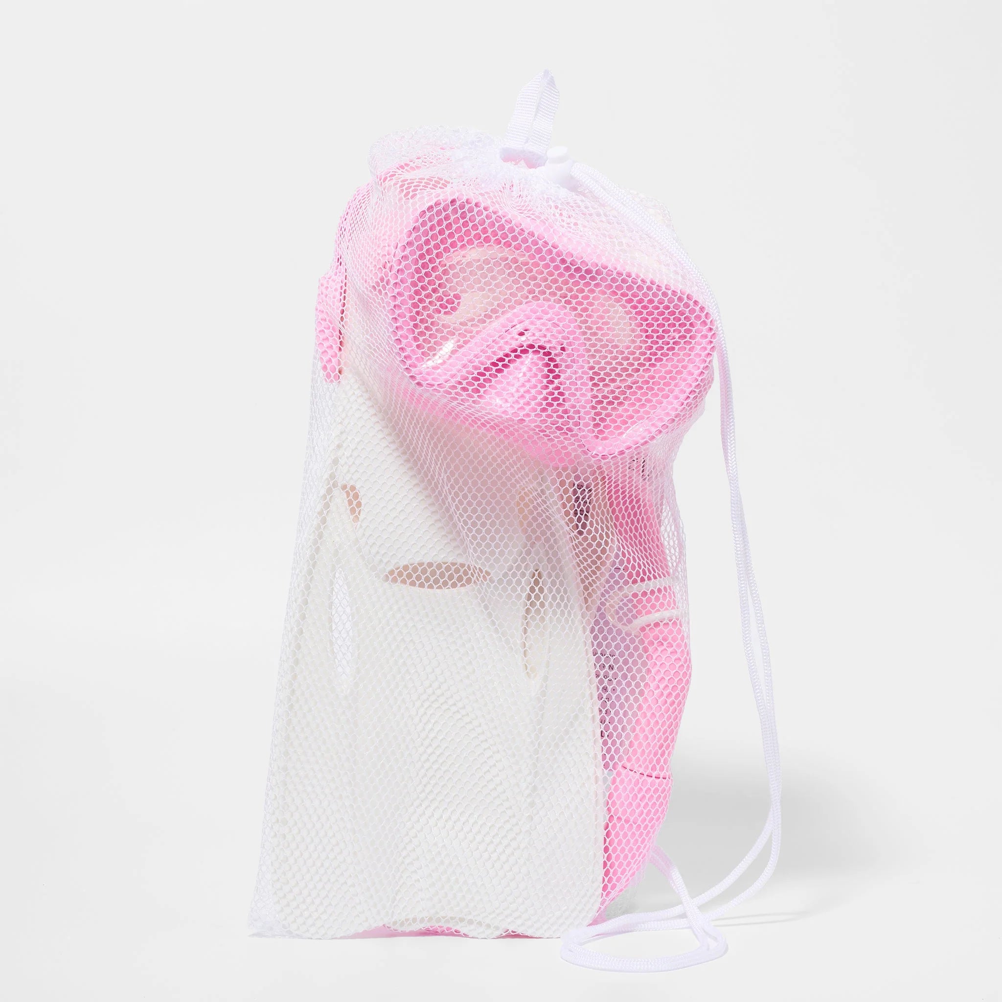 A white mesh drawstring bag containing a pink Kids Snorkel Set by SUNNYLIFE is placed on a plain white background. The snorkel set is partially visible through the mesh fabric, with a carry bag included for convenient transport.