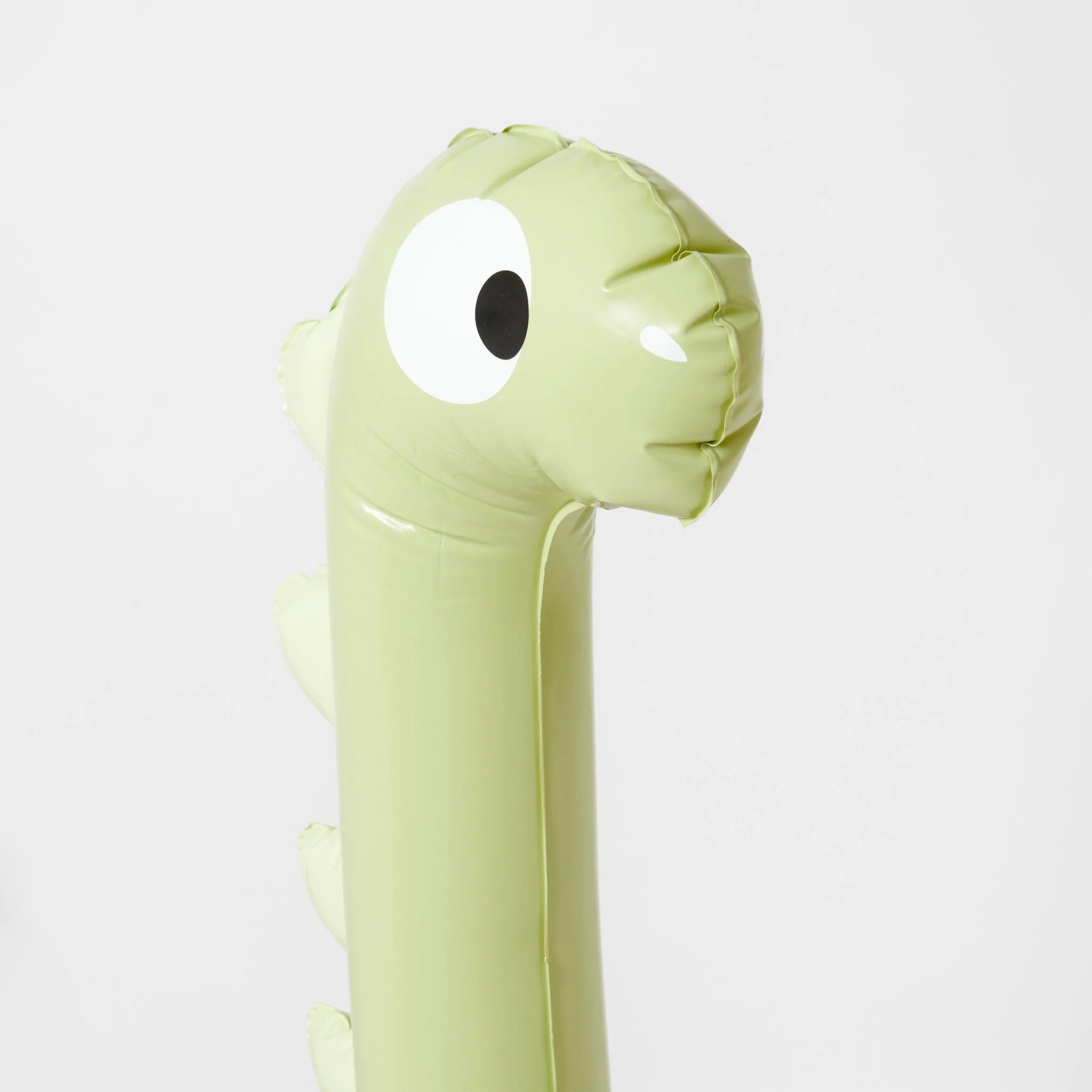 The Dino Giant Sprinkler by SUNNYLIFE is an inflatable green dinosaur with a long neck and large, cartoonish eyes. Made from non-toxic, Phthalate-free, durable PVC, it features a friendly expression and simple design details such as small spikes on its back. The dinosaur is shown against a plain white background.