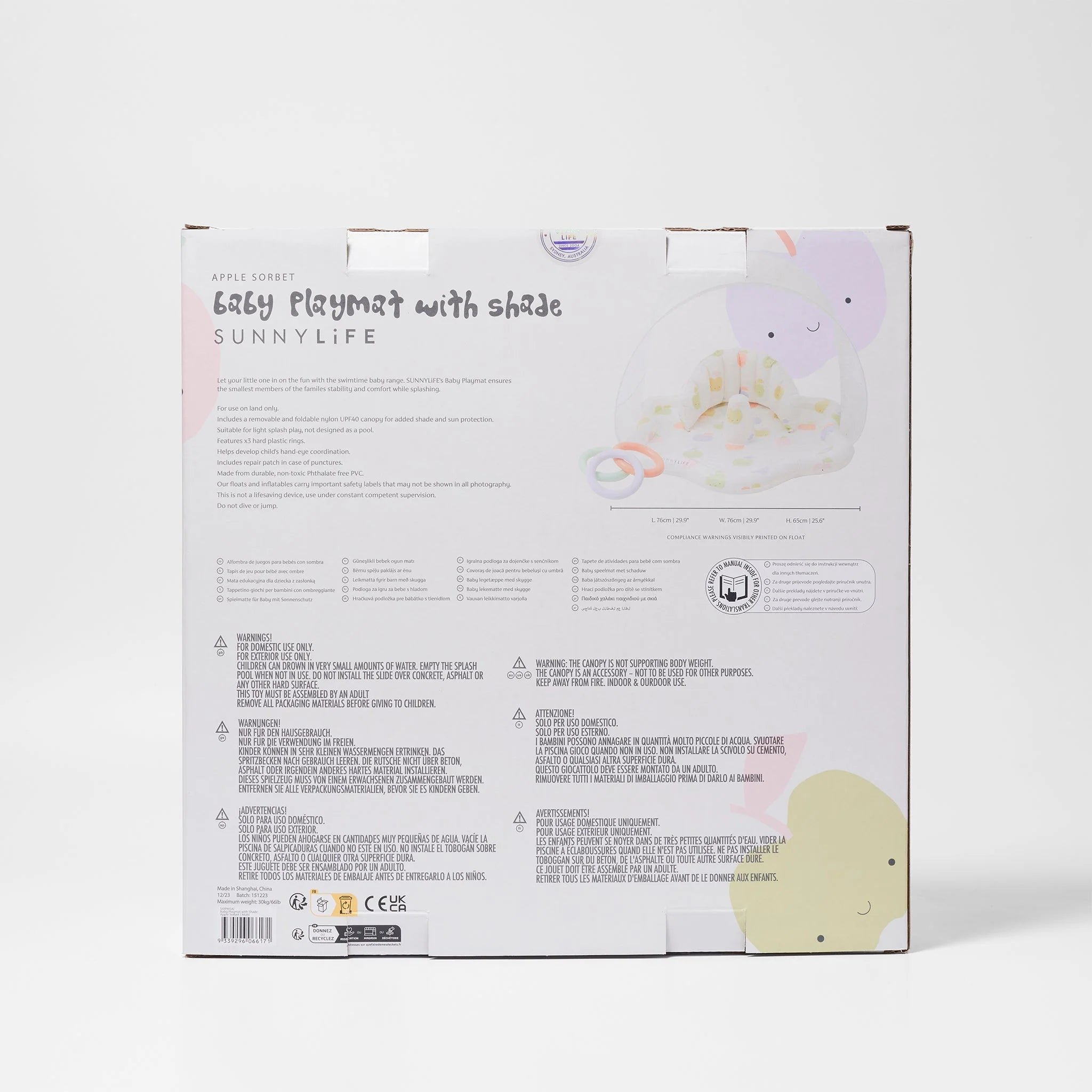 The image shows the back of a packaging box for the "Baby Playmat with Shade" by SUNNYLIFE. The predominantly white box features pastel-colored decorations and text detailing product information and safety instructions, highlighting its UPF40 canopy for extra sun protection.