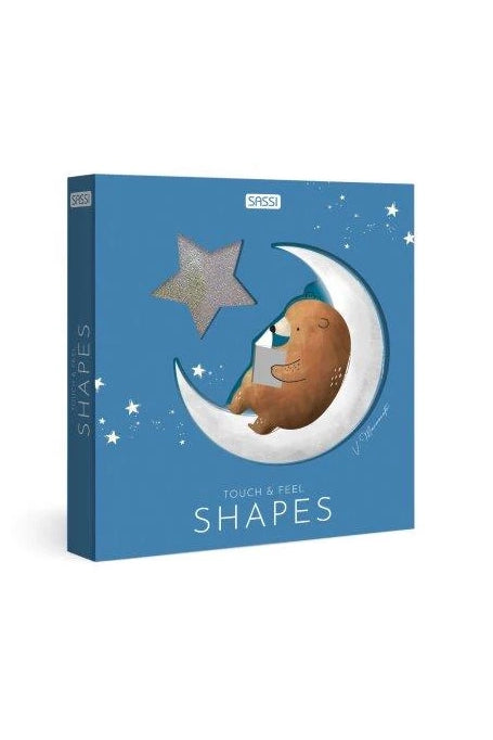 On a vibrant blue box adorned with a crescent moon and bear illustration, SASSI's "Touch & Feel: Shapes" features intriguing cut-out designs. Stars are scattered around the text, inviting you to explore like an interactive book. The bear is perched on the moon, holding a square shape for an engaging experience.