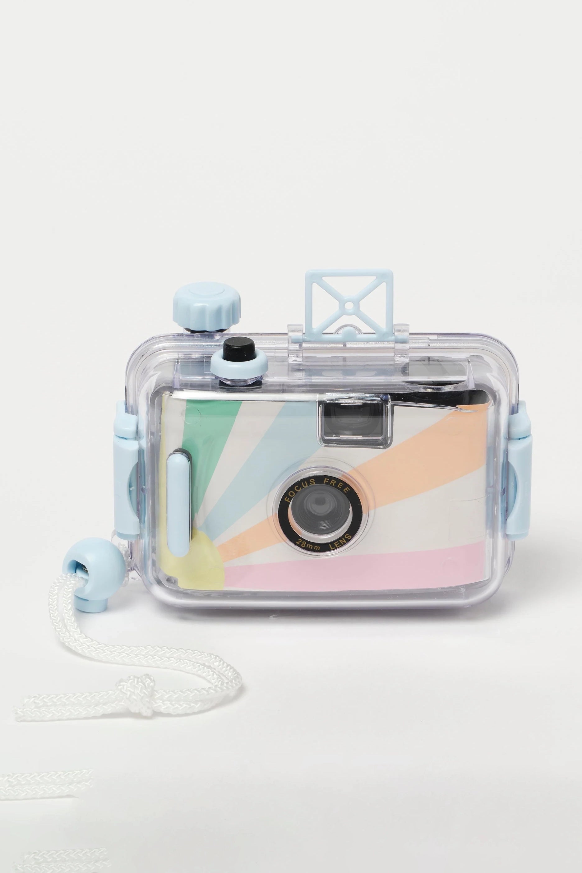 The Underwater Camera Pastel Gelato by SUNNYLIFE is a retro waterproof film camera encased in clear plastic housing, featuring light blue buttons and a beige wrist strap. The camera inside showcases a vibrant rainbow starburst design around the lens and operates on 35mm roll negative film for that vintage touch.