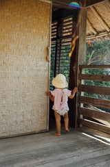 Rear view of toddler girl wearing the Penny blouse and Vali bloomers inside a Balinese hut